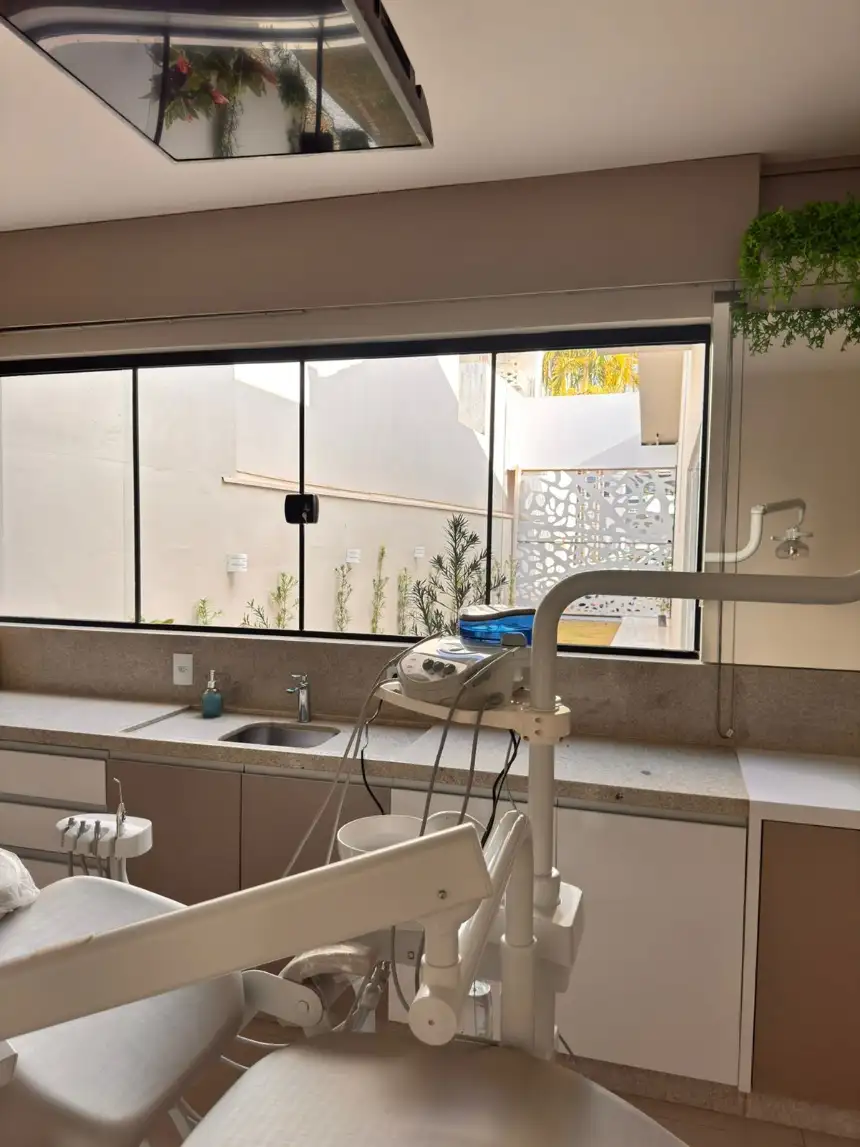 Consultório da OralClin: cadeira odontológica com equipo, bancada e janela ampla com luz natural.