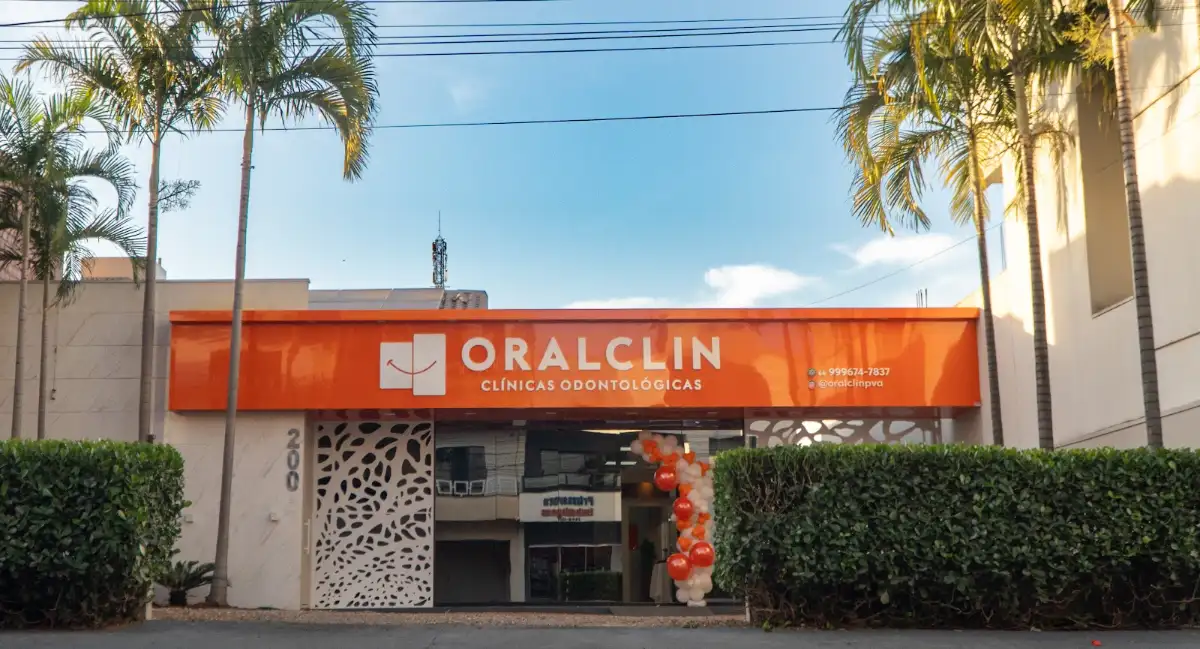 Fachada da OralClin na Rua Paranatinga: toldo laranja com o letreiro ORALCLIN Clínicas Odontológicas, palmeiras e jardim na frente.